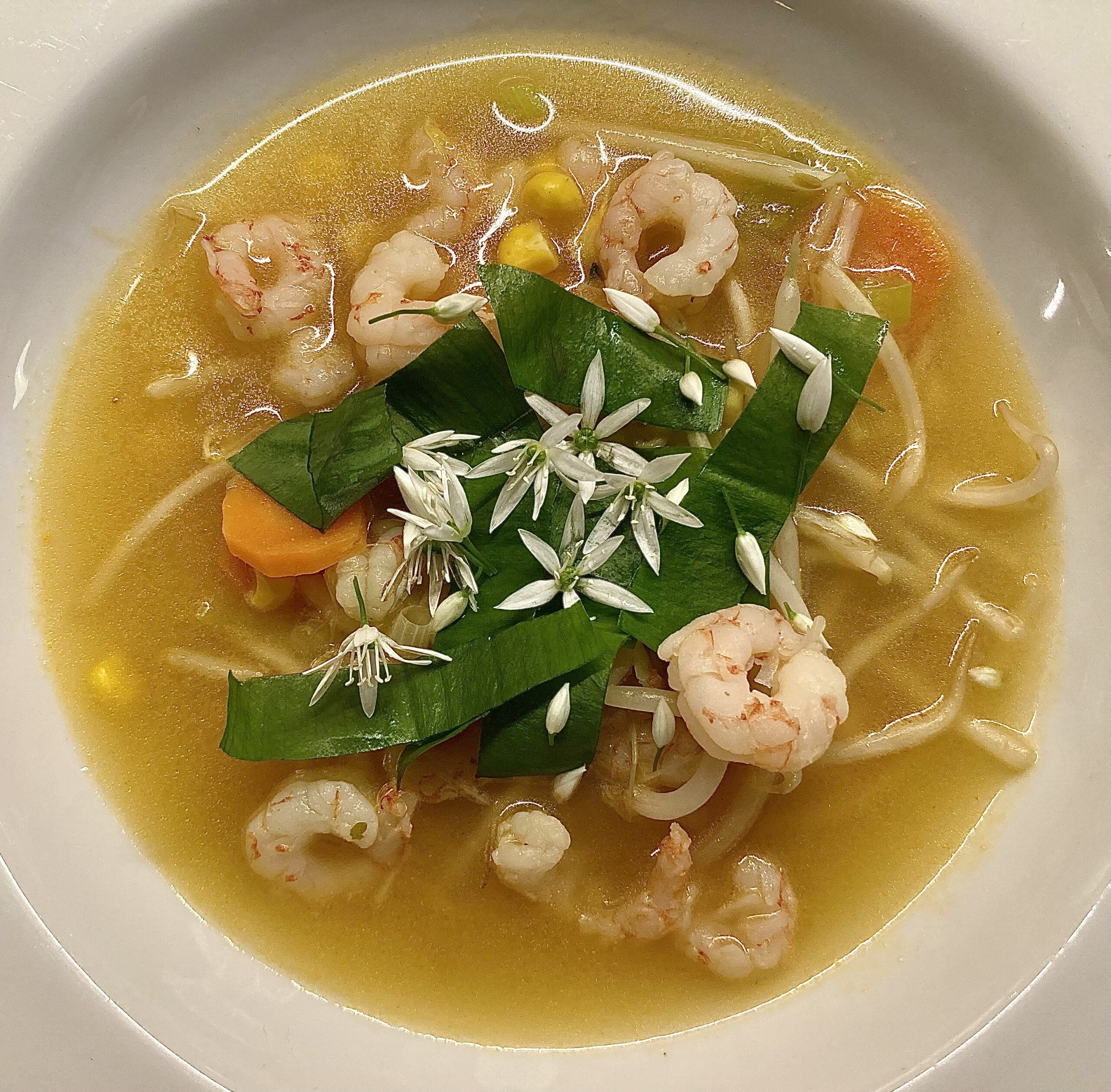 Thai-style broth with prawns, beansprouts, and carrots - plus shredded garlic leaves.