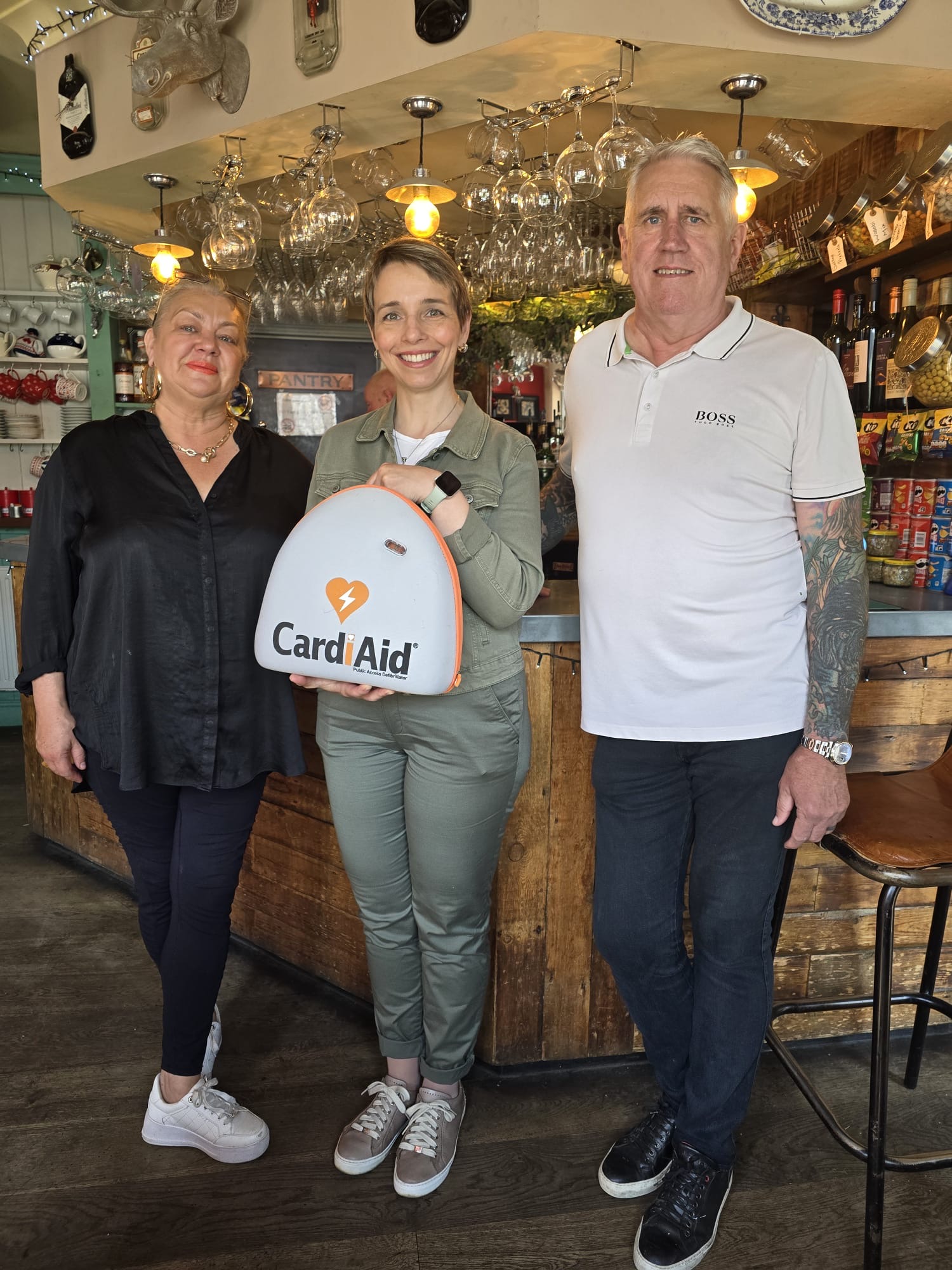 Nicola Hackett (left) receives the defibrillator from a team from Harpenden Orthodontics.
