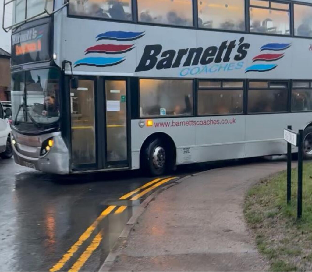 A double decker bus mounting the pavement at the junction of Green Lane and High Oaks.