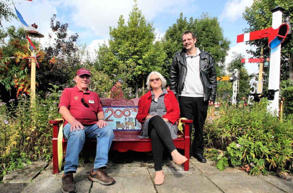 The bench installation at The St Albans South Signal Box Museum Heritage Open Day event on Saturday 13 th September – pictured is Judith Carruthers Engagement Manager London & South Region of The National Lottery Heritage Fund, seated on the bench with John Telford, Chair of the St Albans South Signal Box Trust and Emmaus Hertfordshire companion Lee